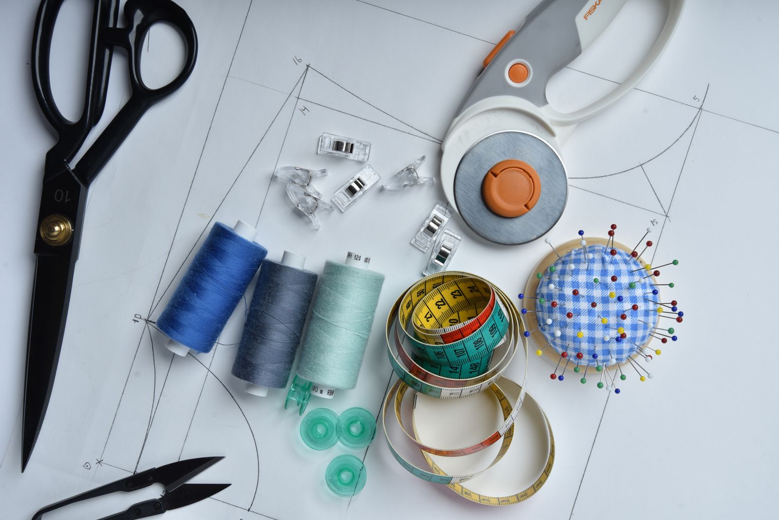Sewing tools, paper pattern pieces, thread, and scissors arranged for a shorts sewing pattern project