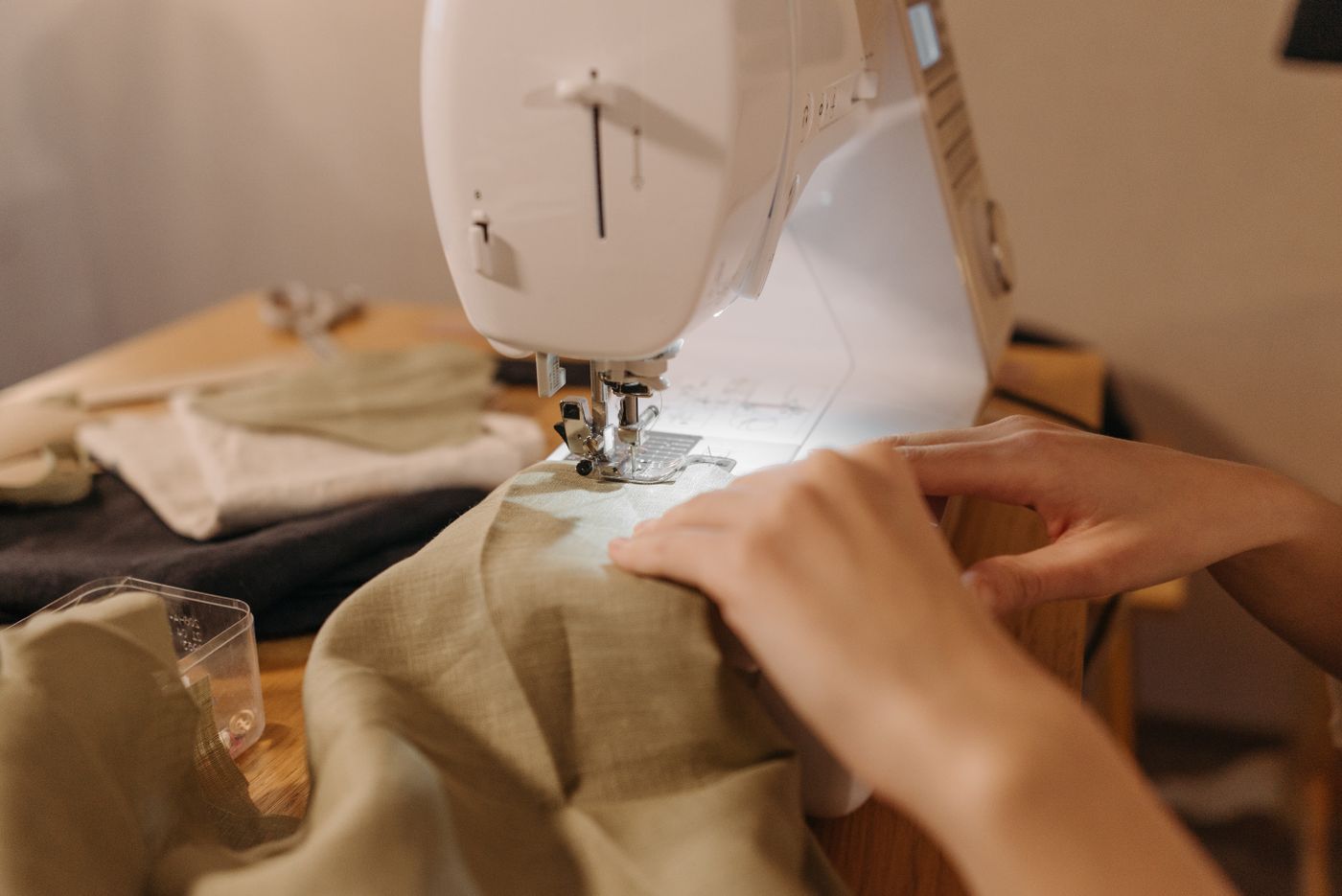 Hands guiding fabric under a sewing machine while sewing shorts seams